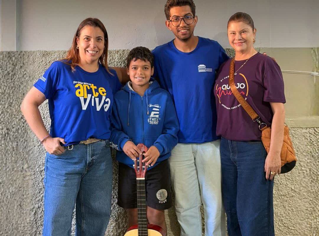 Aluno e equipe do Programa Arte Viva em Patrocínio posam com o violão entregue ao menino
