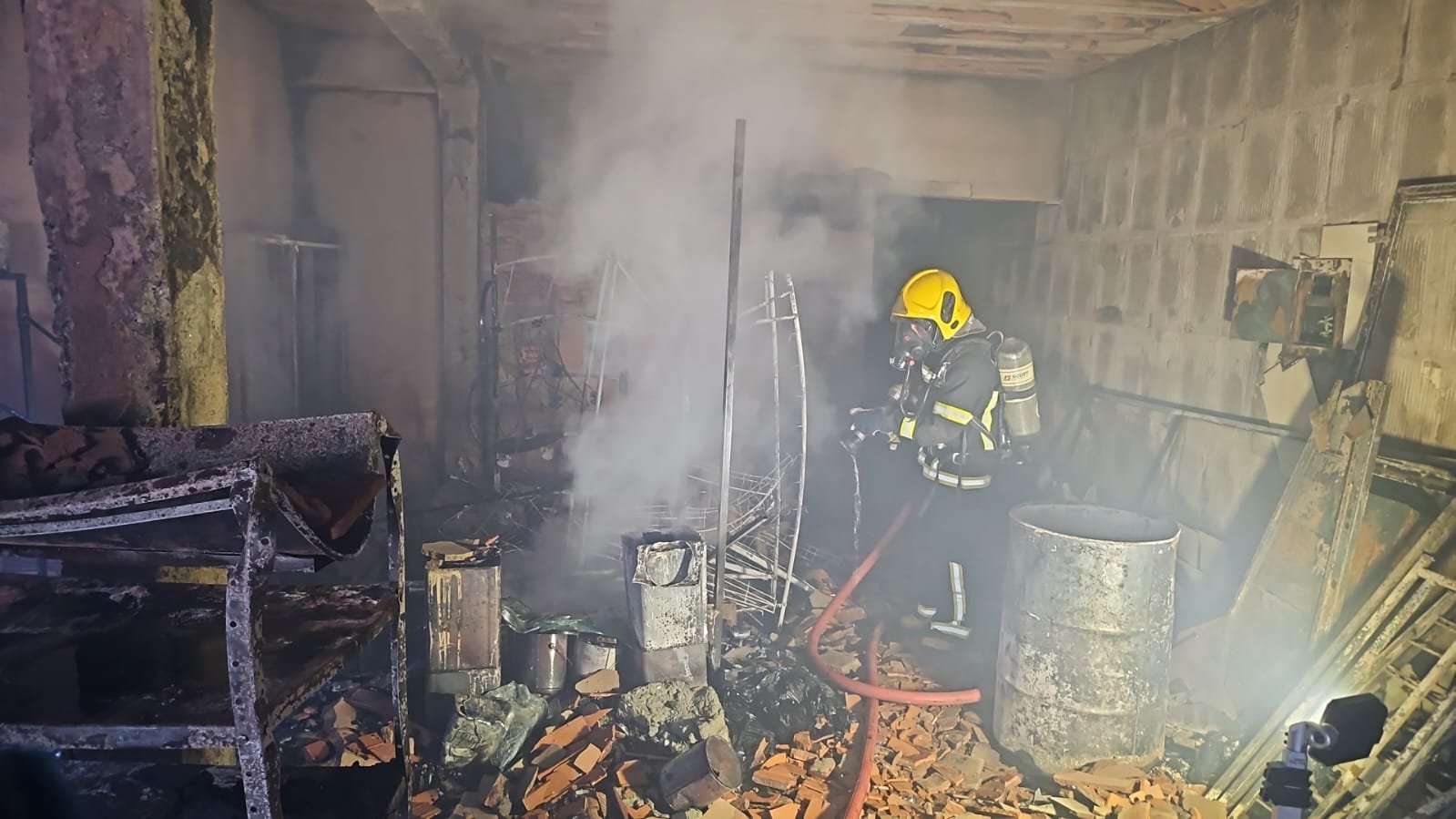 Bombeiro faz o rescaldo dentro da construção atingida pelo incêndio em Romaria