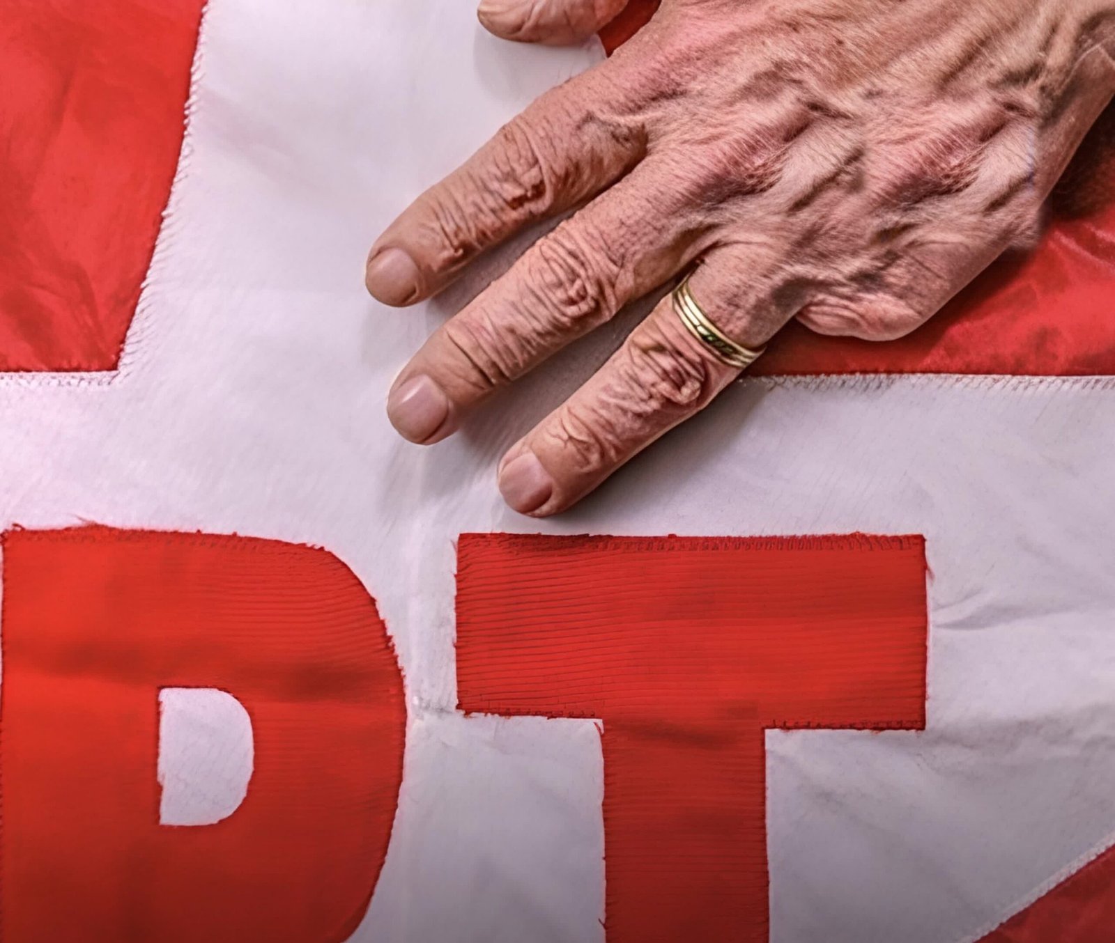 Mão apoiada sobre bandeira do PT, imagem usada para ilustrar a frase de Maria da Conceição Tavares citada por Lula