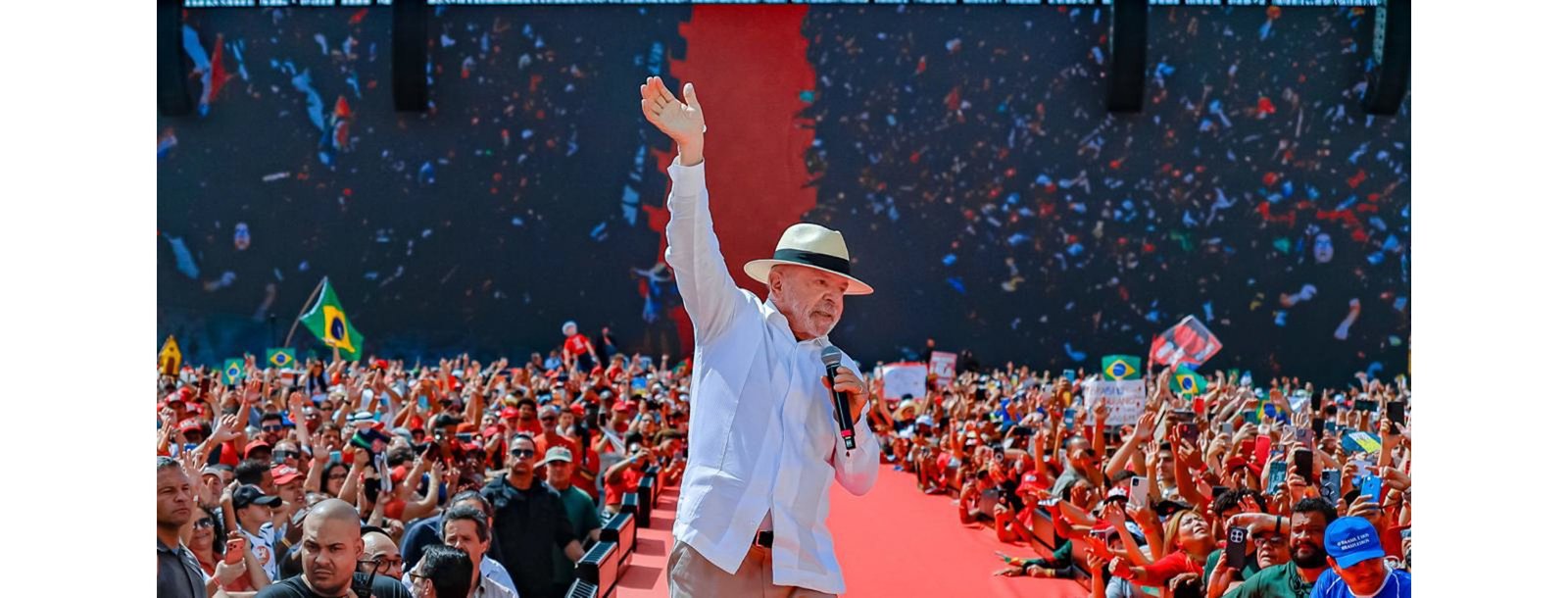 Lula de chapéu branco acena no palco do ato da Vila Euclides, cercado por multidão, na investigação contra Lula aberta pelo TSE