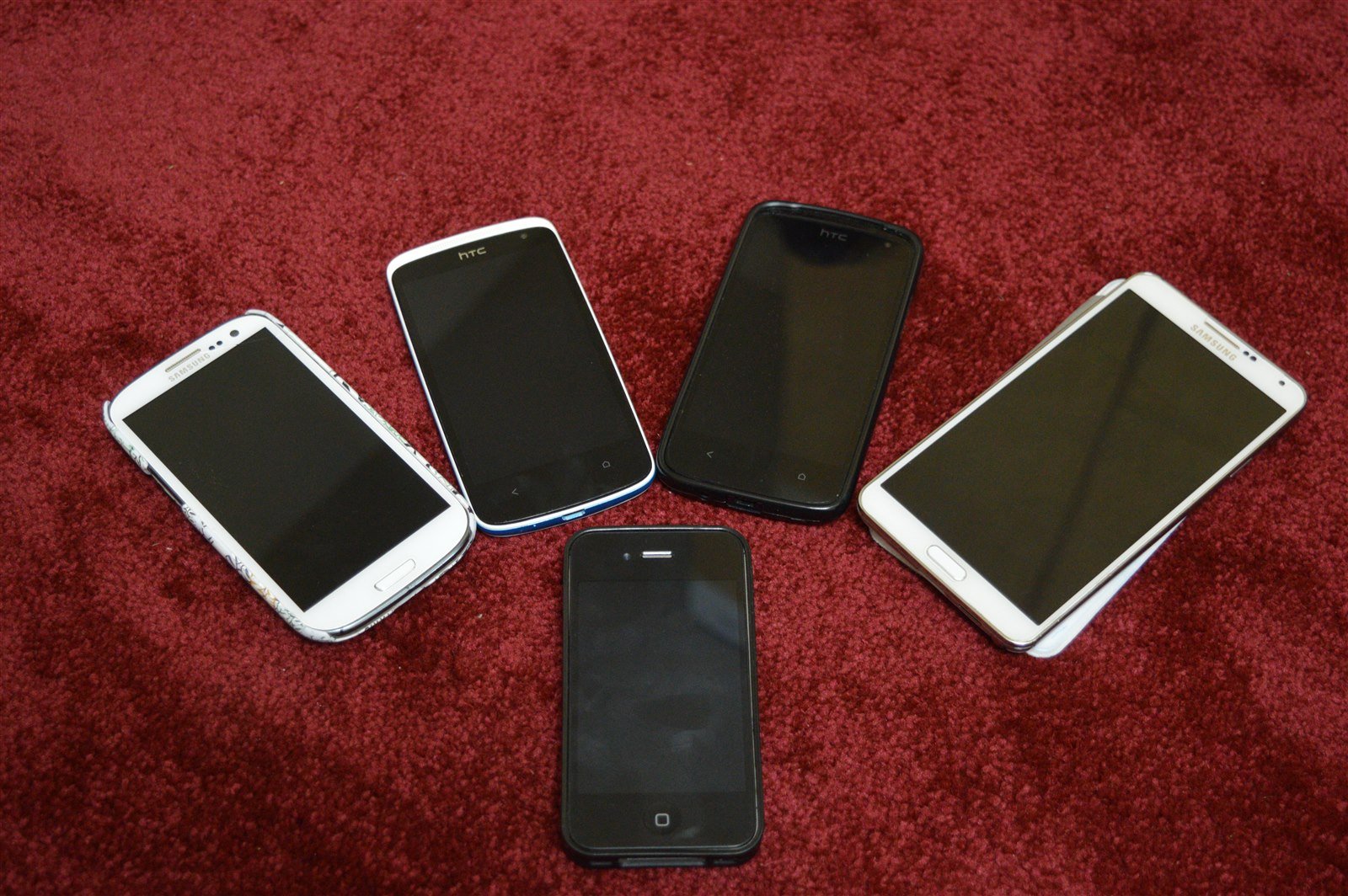 Cinco smartphones de modelos diferentes enfileirados sobre uma mesa