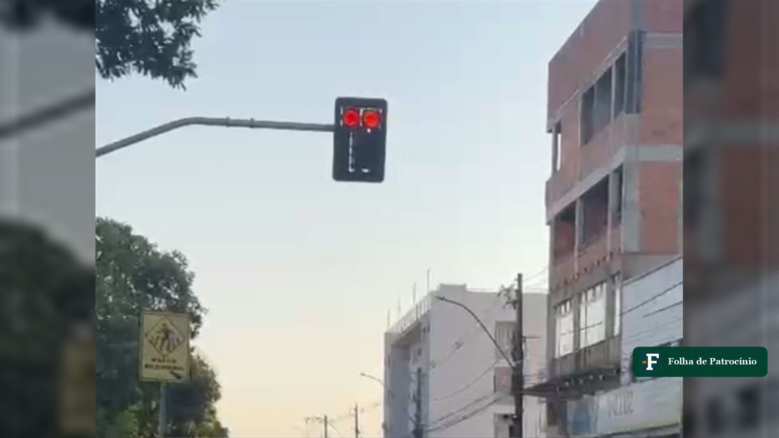 Semáforo em cruzamento movimentado no trânsito de Patrocínio, com prédios do comércio ao fundo