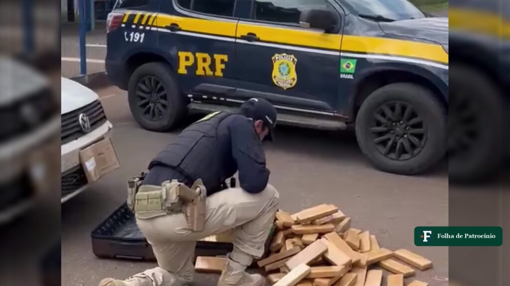 Policial da PRF agachado ao lado de mala com tabletes de maconha em frente a viatura, em Patos de Minas. Foto: PRF/Divulgação