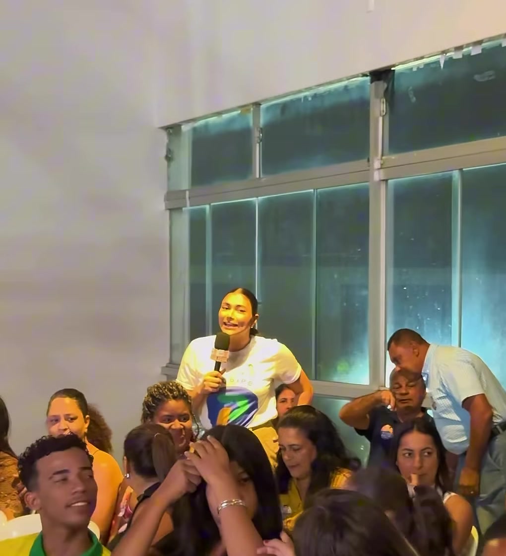 Apoiadores sentados no salão durante o encontro do PL em Patrocínio, com uma apresentadora da campanha ao fundo