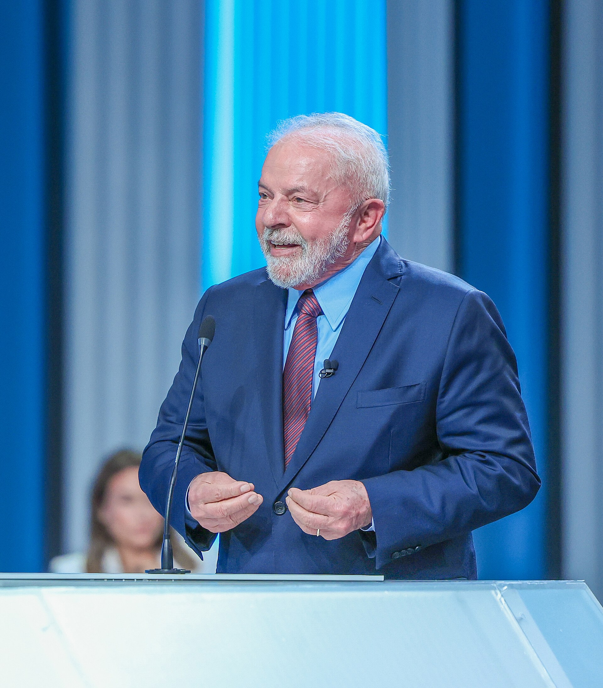 Lula sorri ao microfone no debate da Globo de 2022, de terno azul e gravata vinho