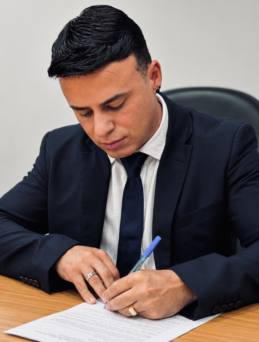 Prefeito de Três Marias, José Augusto, de terno escuro, assina o termo de posse em uma mesa