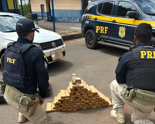 Policiais da PRF ao lado dos tabletes de maconha empilhados em frente a uma viatura em Patos de Minas