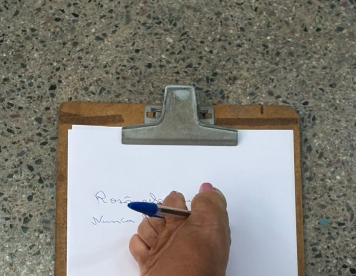 Mão de participante escreve em prancheta na roda de conversa do Setembro Verde no CRAS José Ribeiro, em Patrocínio