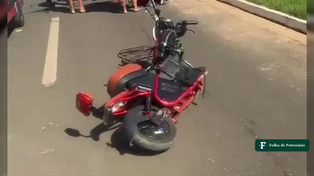 Moto elétrica vermelha caída na pista da Avenida Alberto Sanarelli após acidente com moto elétrica em Patrocínio