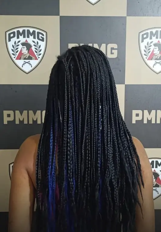 Mulher presa de costas diante do painel da Polícia Militar depois da agressão em João Pinheiro