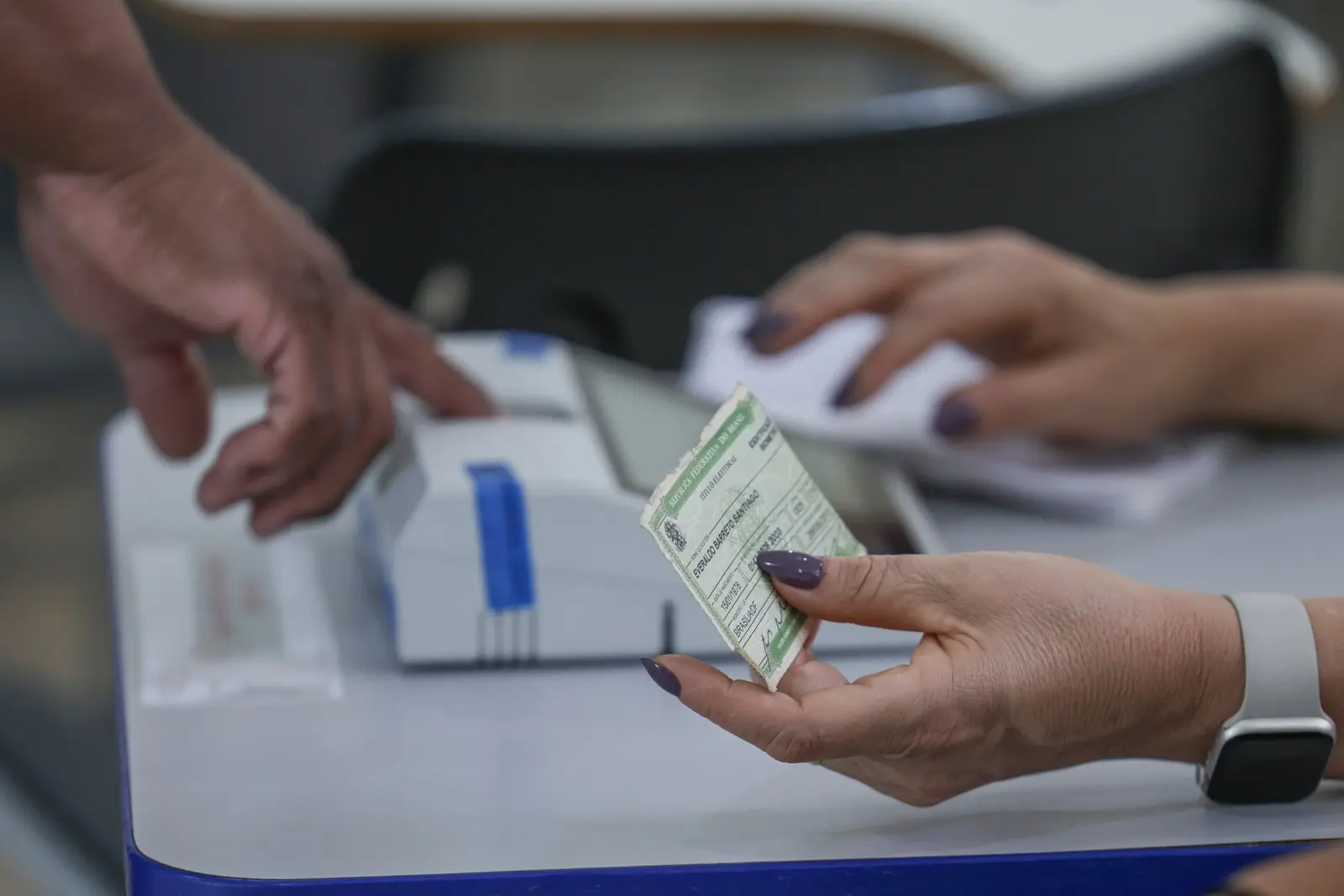 Apuração do segundo turno: eleitor segura o título ao lado do leitor biométrico da seção