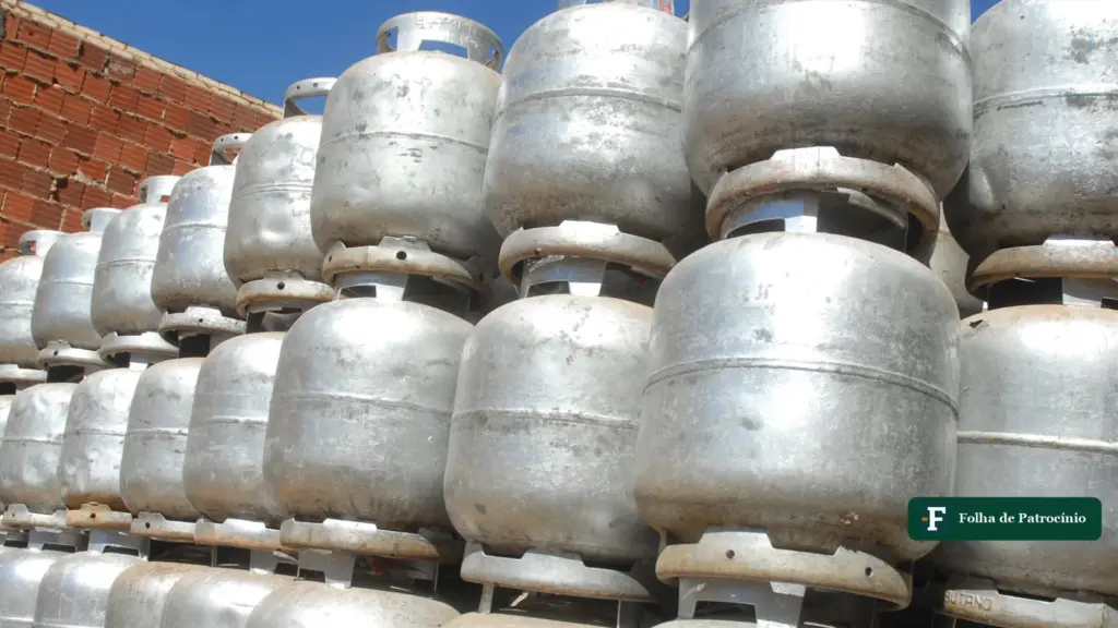 Pilha de botijões de gás de cozinha de 13 kg diante de uma parede de tijolos