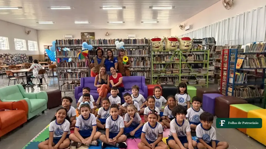 Crianças sentadas em tapetes coloridos entre as estantes durante a Aventura na Biblioteca em Patrocínio