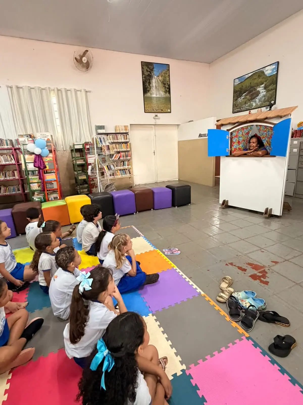 Contação de histórias com teatro de fantoches na biblioteca, na Aventura na Biblioteca em Patrocínio, com crianças sentadas no chão