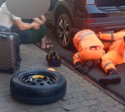 Militares do Corpo de Bombeiros agachados ao lado de um carro na Rua Presidente Vargas, no Centro de Patrocínio, durante o atendimento a um gato preso no carro