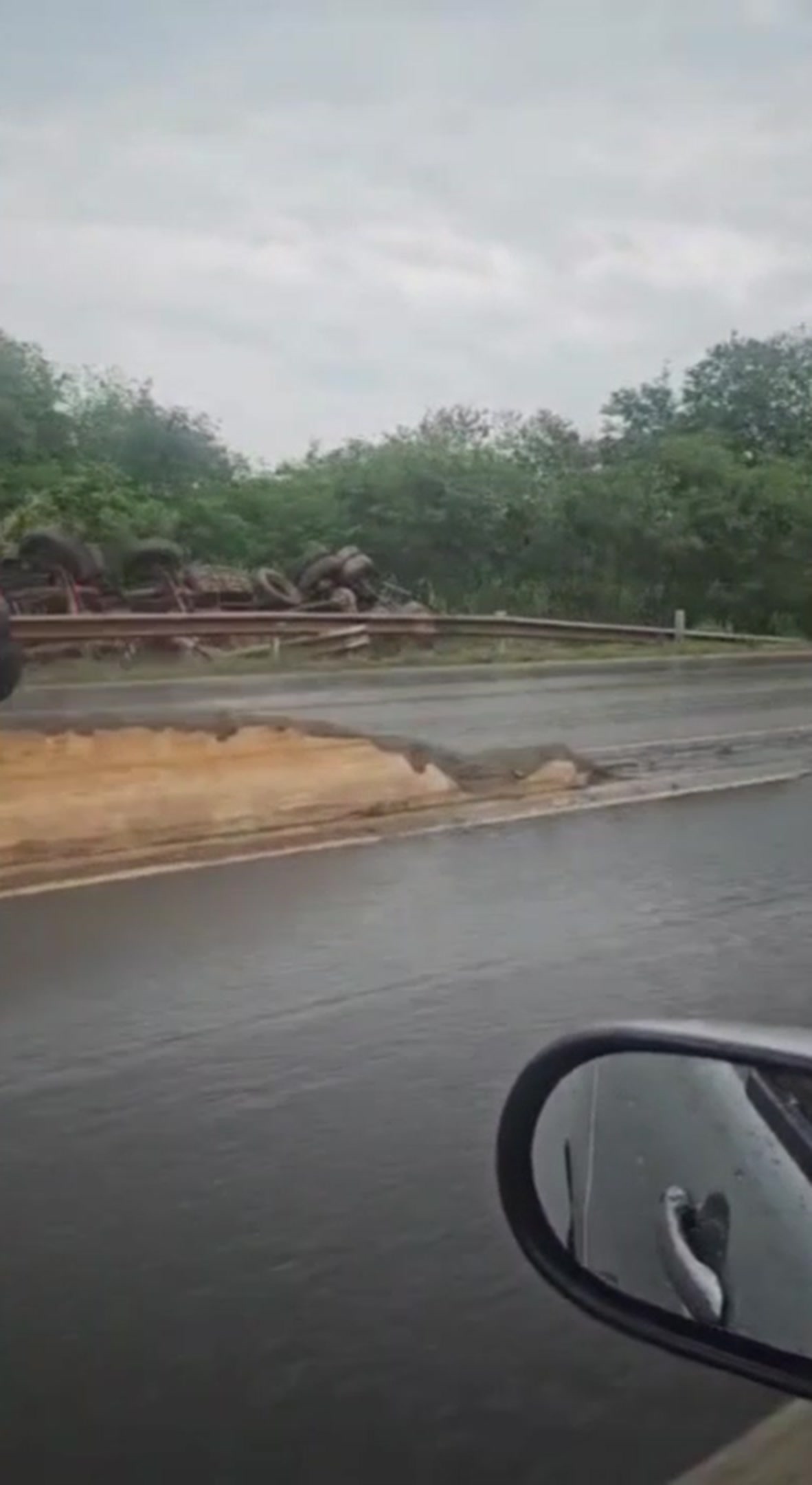 Caminhão tombado ao lado do guard-rail de uma rodovia molhada, em um dos acidentes em Patos de Minas