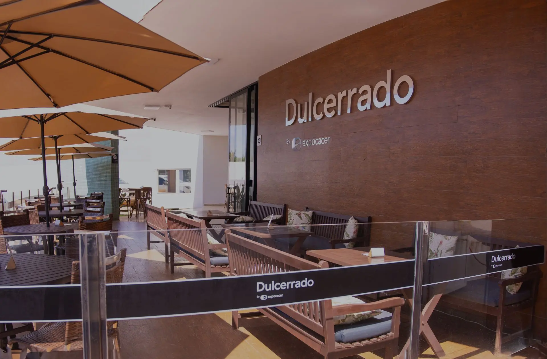 Varanda da cafeteria Dulcerrado, em Patrocínio, com mesas e logotipo na parede