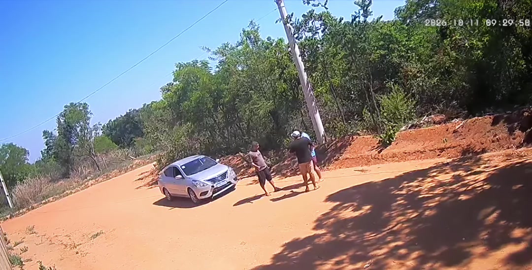 Imagem de câmera de segurança em estrada de terra com carro branco e várias pessoas, no vídeo da confusão com vereador