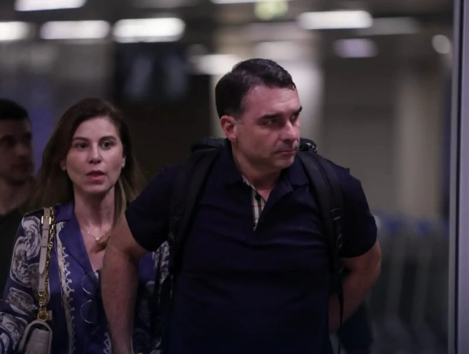 Autor da carta de Flávio, o senador caminha com a mulher, Fernanda, em aeroporto