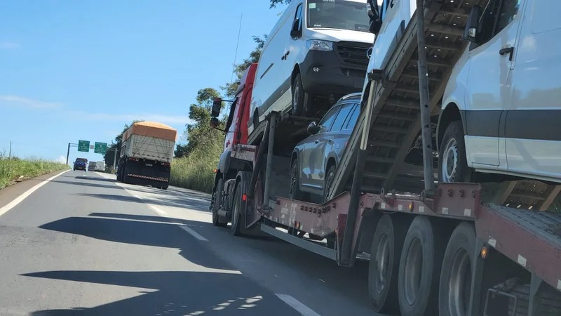Veículos de grande porte, uma cegonheira e uma carreta, circulando em rodovia estadual de Minas