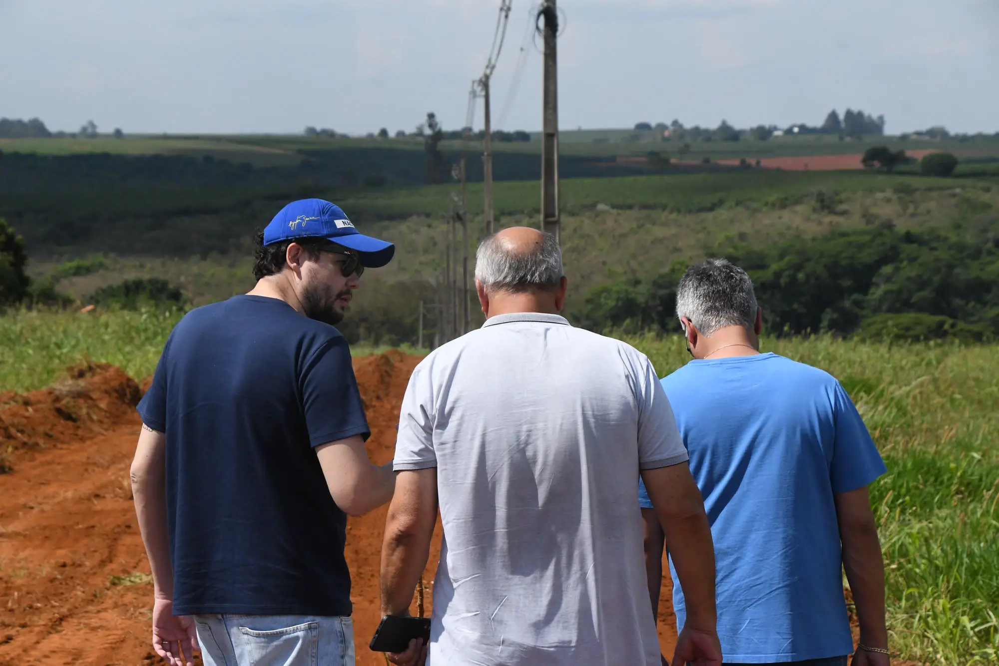 Três homens observam área de expansão urbana, onde ruas novas aguardam CEPs em Patrocínio