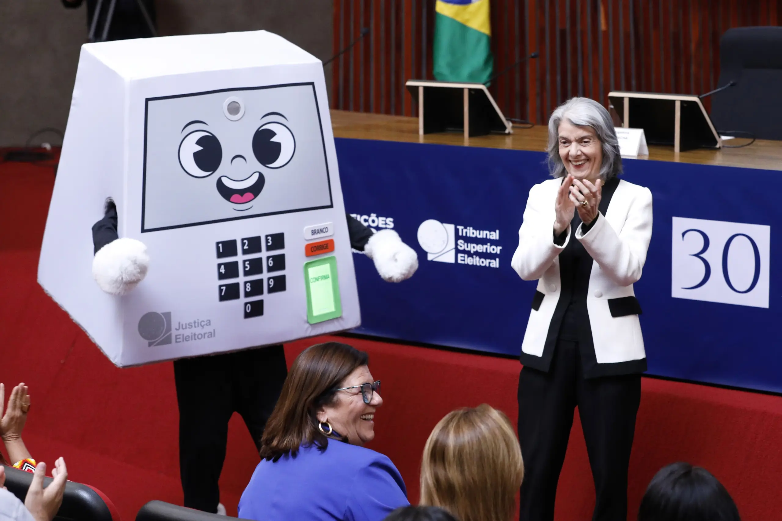 Mascote da urna eletrônica em evento do TSE, cena sobre como termina o segundo turno