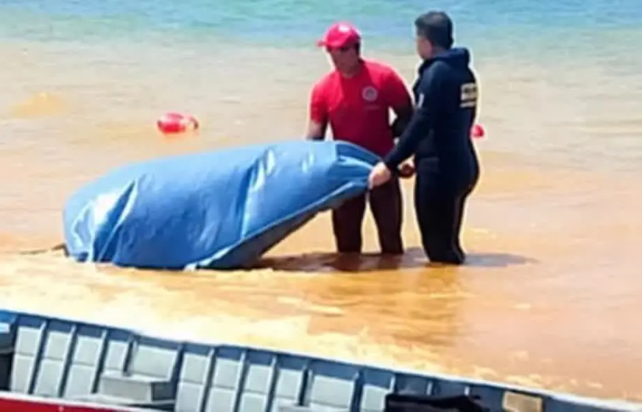 Equipe com lona azul no raso da represa durante o corpo encontrado em Três Marias