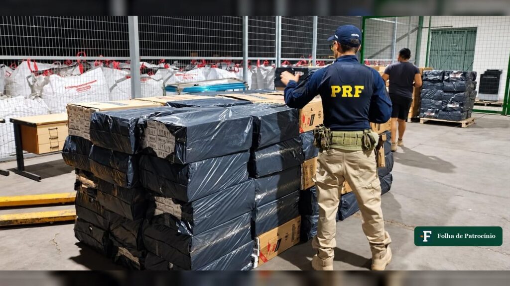 Policial rodoviário federal ao lado de pilhas de fardos com os 105 mil maços de cigarros apreendidos na BR-262. Foto: PRF