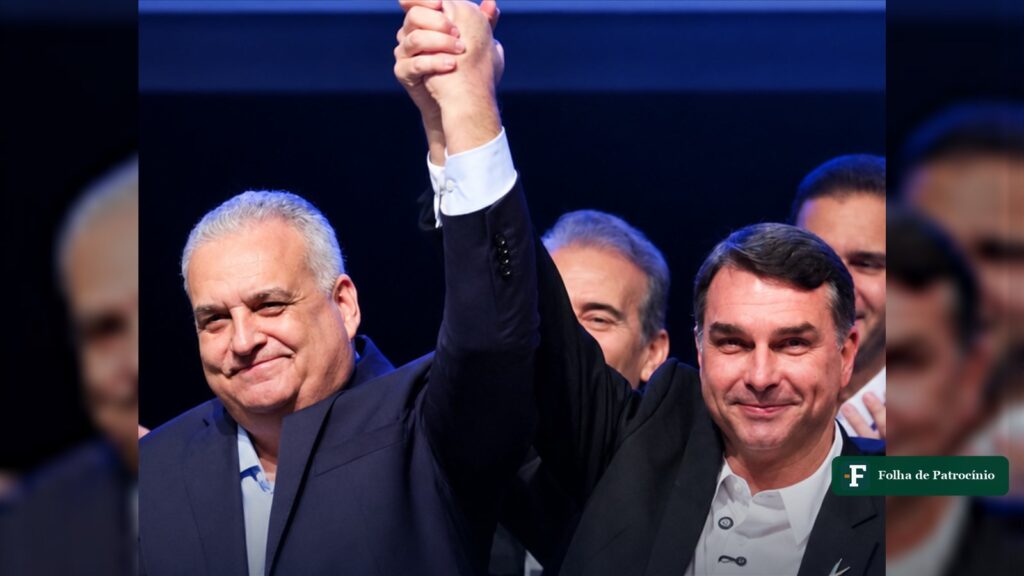 Alfredo Gaspar, candidato a vice, e Flávio Bolsonaro de mãos dadas e erguidas em evento da chapa (reprodução)