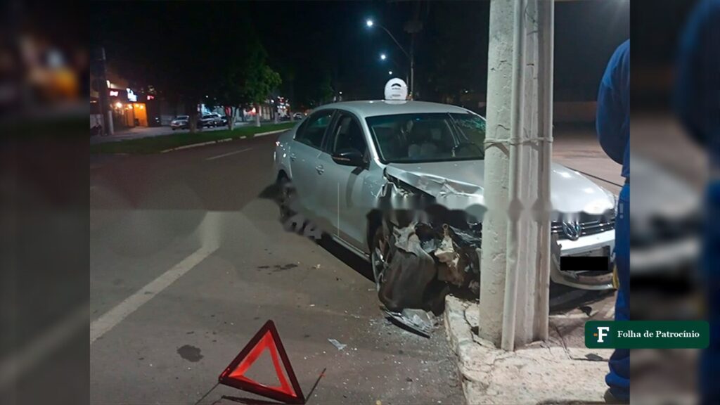 Carro prateado com a frente amassada junto a poste durante a noite após crise convulsiva ao volante, em Patrocínio