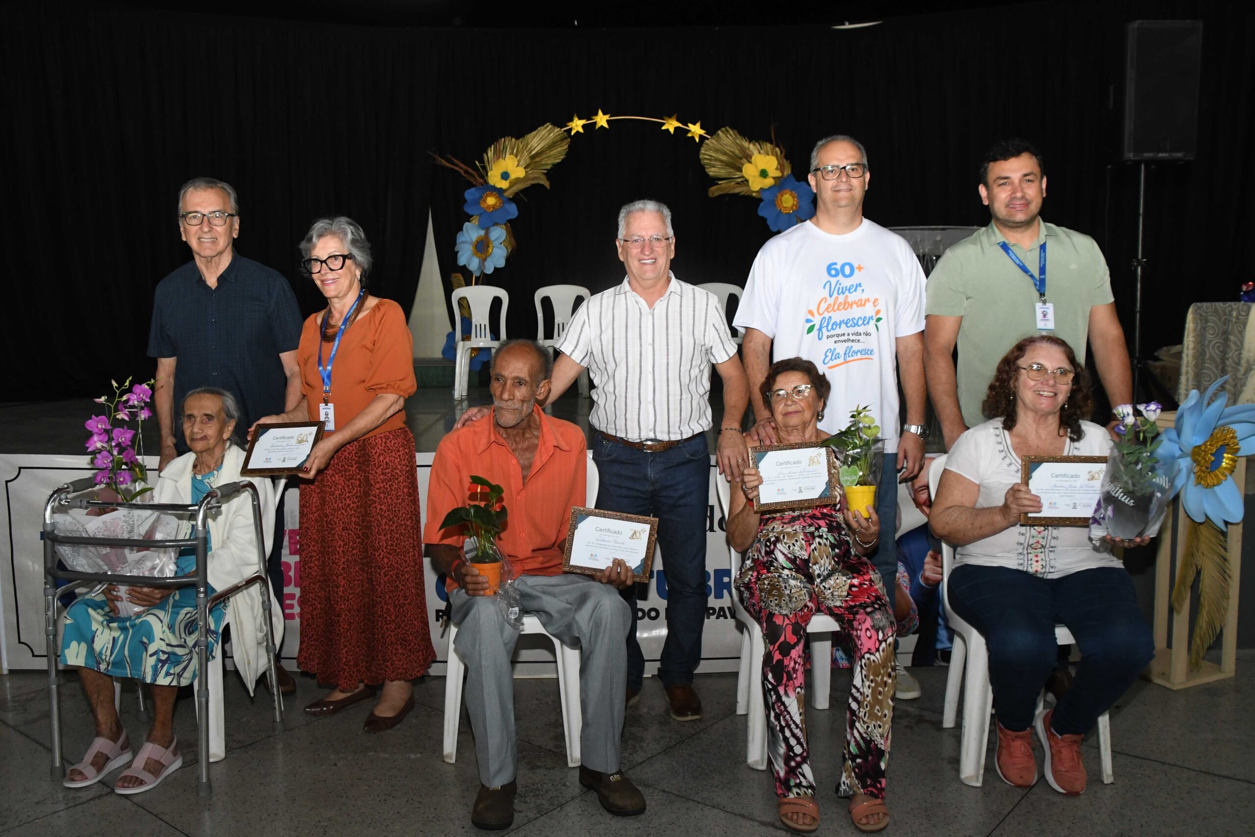 Participantes do Dia da Pessoa Idosa reunidos em grupo no palco do Rotary Clube Brumado dos Pavões