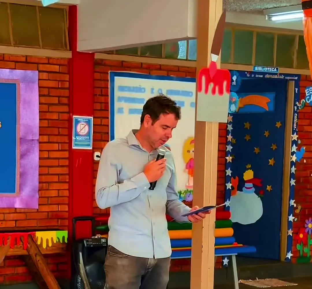 Participante do Emprega+ em Patrocínio fala com alunos sentados no pátio da escola