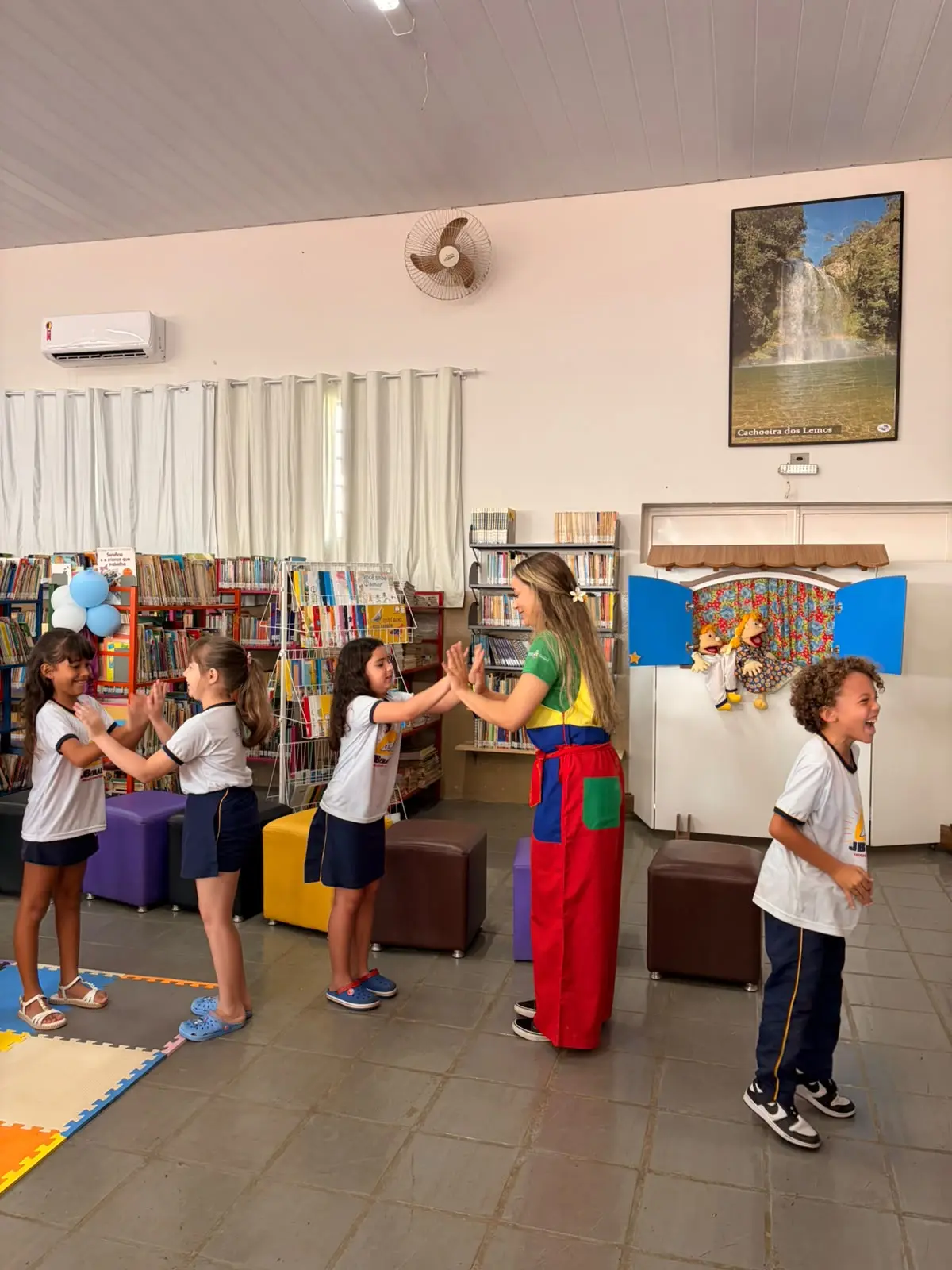 Contadora de histórias faz brincadeira de bater as mãos com alunos da Escola Municipal João Beraldo na Biblioteca Pública Municipal