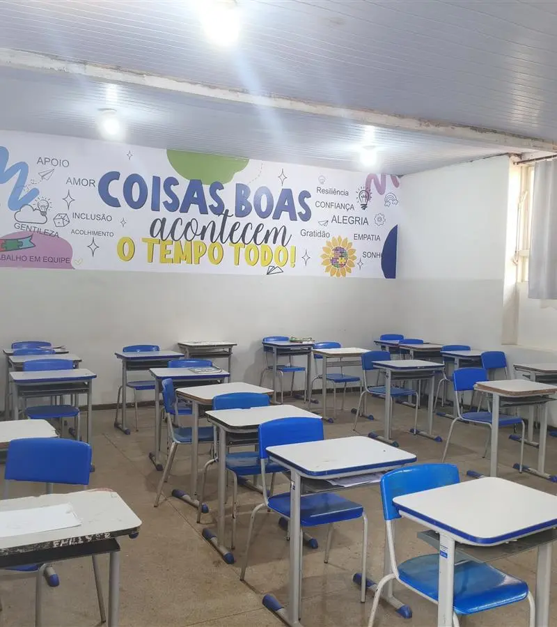 Sala de aula com carteiras azuis e painel na parede, ilustração do debate sobre a escolaridade de Lula