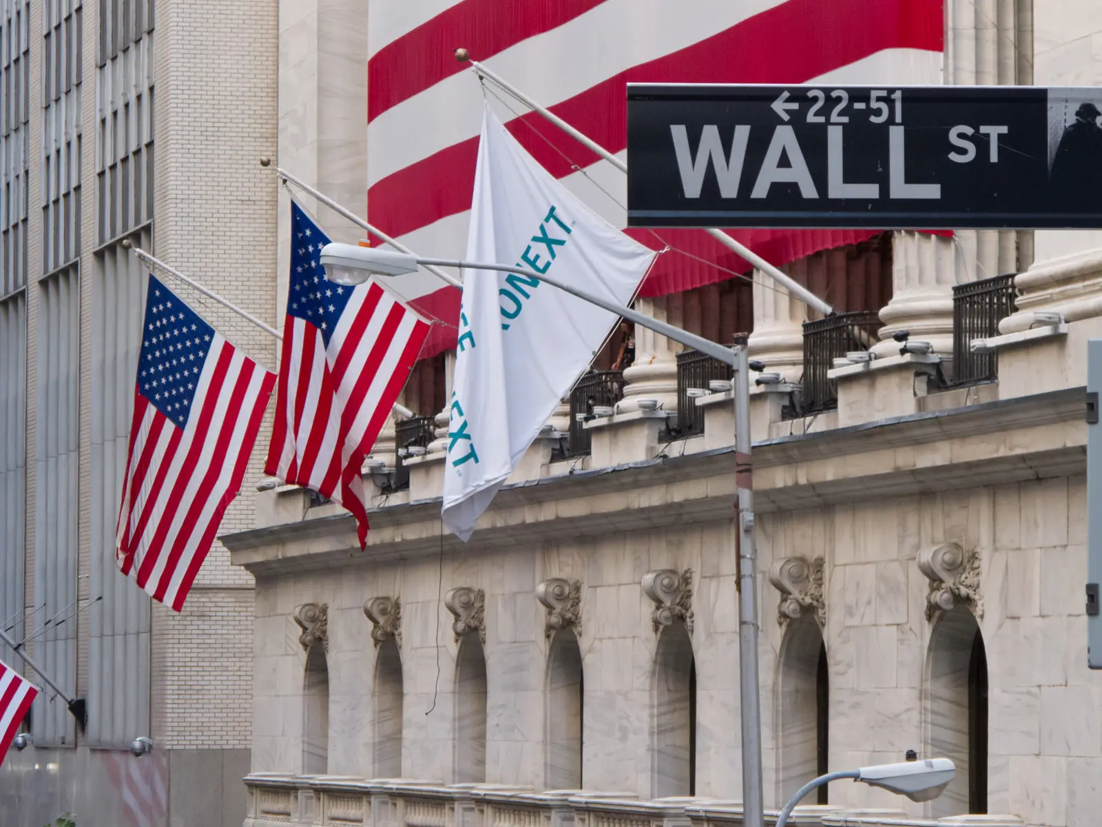 EWZ cai: Wall Street e a fachada da Bolsa de Nova York, com bandeiras dos Estados Unidos