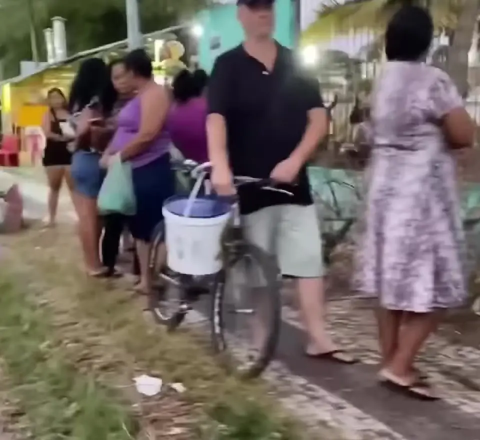 Pessoas com baldes e bicicleta na fila por ossada em Fortaleza