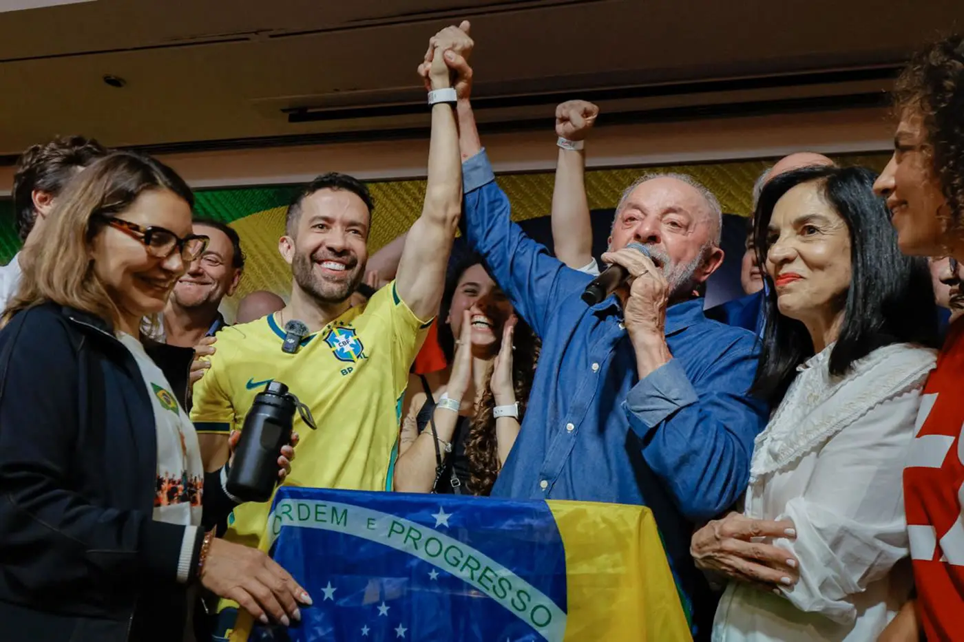Lula discursa com o microfone na mão, cercado de apoiadores, após a reeleição, em São Paulo