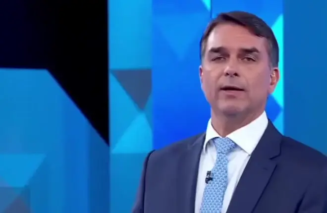 Flávio Bolsonaro em pé no estúdio do debate da Globo, onde cobrou Lula por obras paralisadas