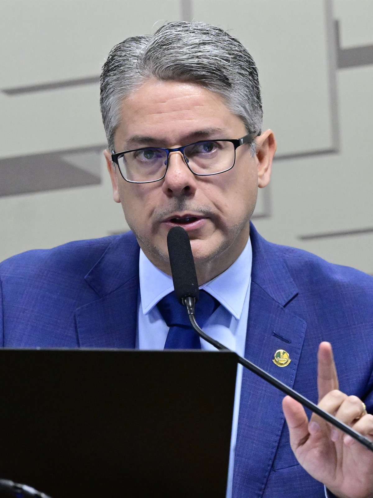 Alessandro Vieira, um dos senadores eleitos em Sergipe, de terno azul e óculos falando ao microfone como relator da CPI do Crime Organizado