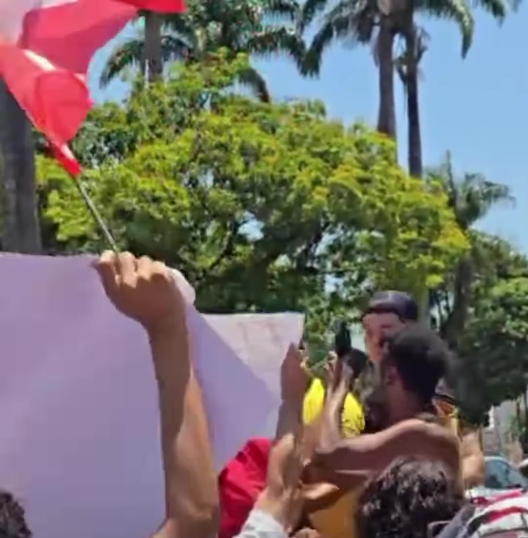 Homem de camisa preta em carroceria de caminhonete cercado de manifestantes na confusão em Patos de Minas