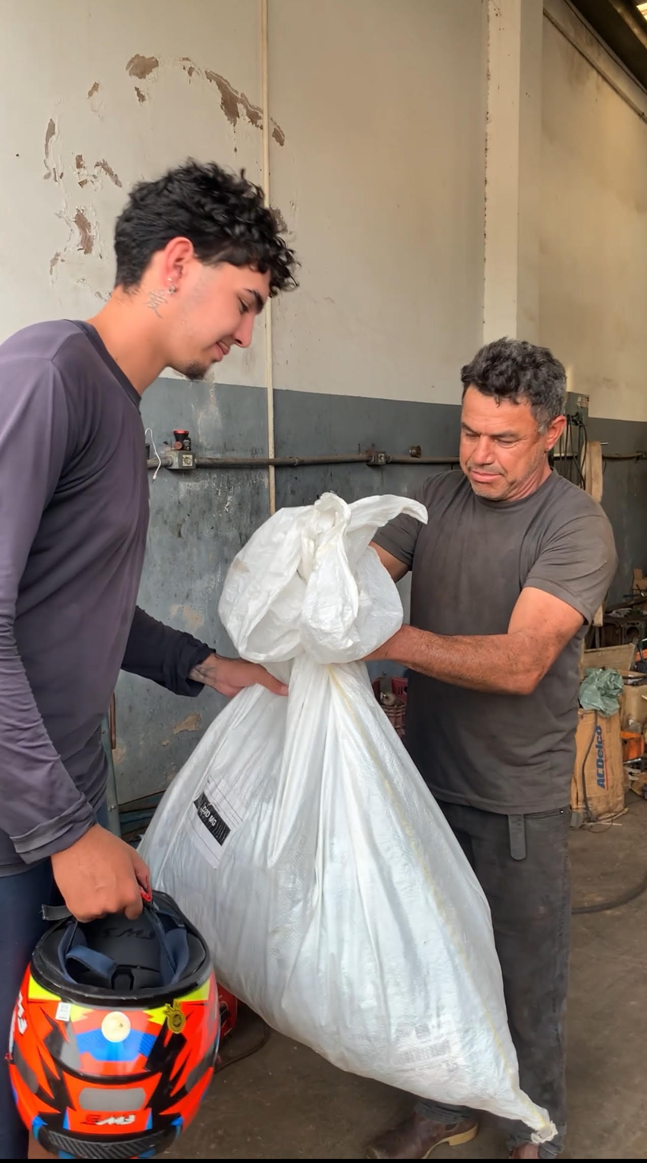 Mecânico entrega ao entregador o saco com produtos perdidos na Avenida Faria Pereira, em Patrocínio