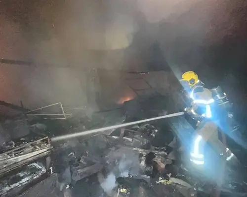 Militar do Corpo de Bombeiros joga água sobre destroços durante o incêndio em Patos de Minas, no bairro Cristo Redentor