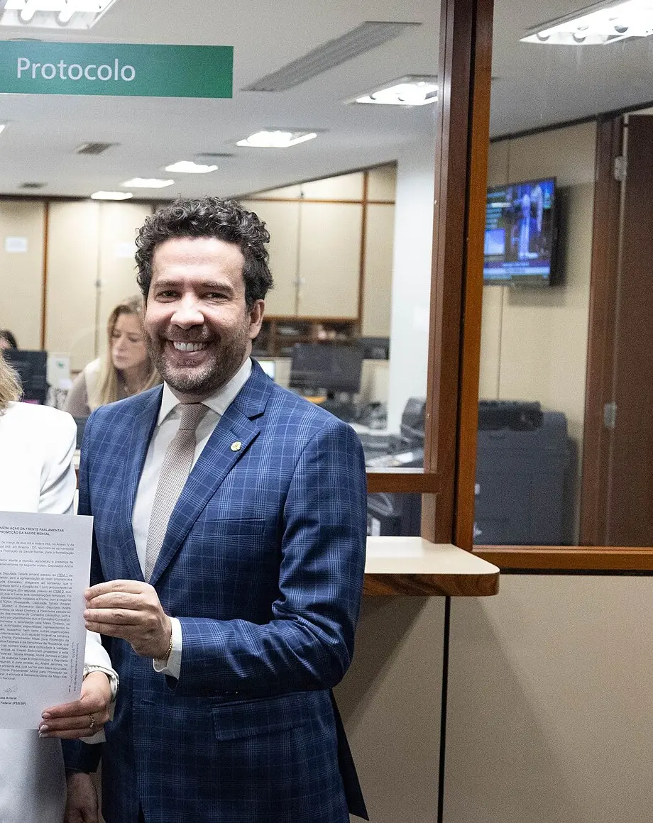 Live de Janones: o deputado André Janones sorri segurando um documento na Câmara dos Deputados