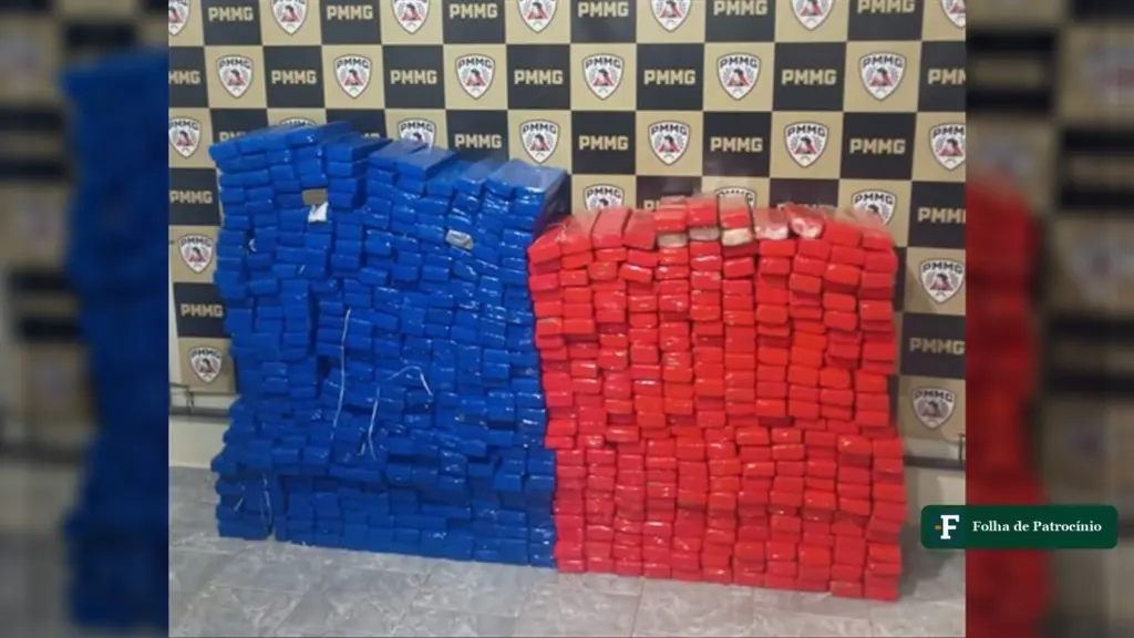 Barras de maconha em embalagens azuis e vermelhas empilhadas diante do painel da PMMG