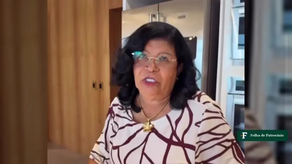 A mãe de Carlinhos Maia, dona Maria, gesticula e fala numa cozinha, em quadro de vídeo de 2026