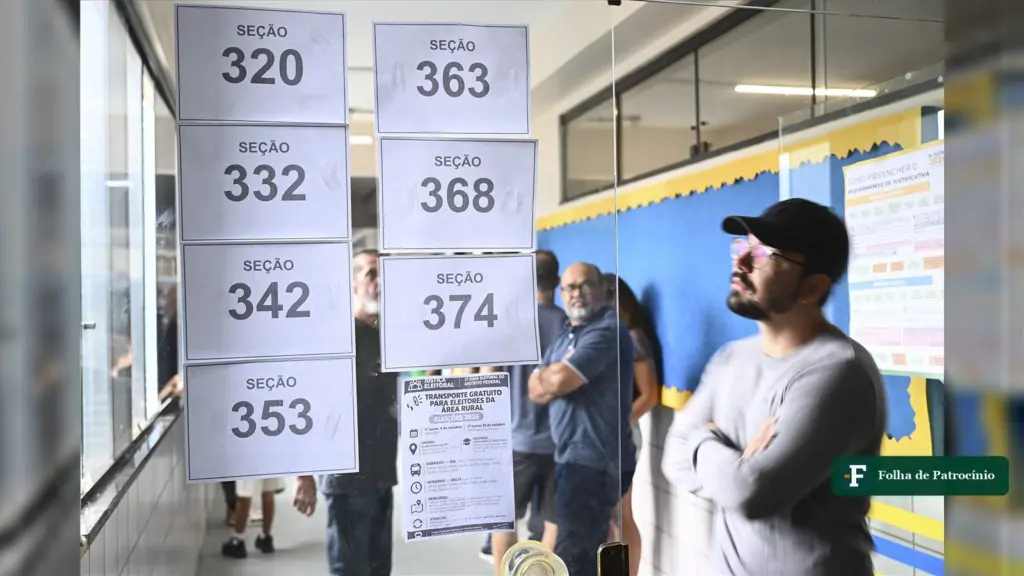 Eleitor procura o número da seção nas placas de uma escola, cena de mudança de local de votação no 1º turno