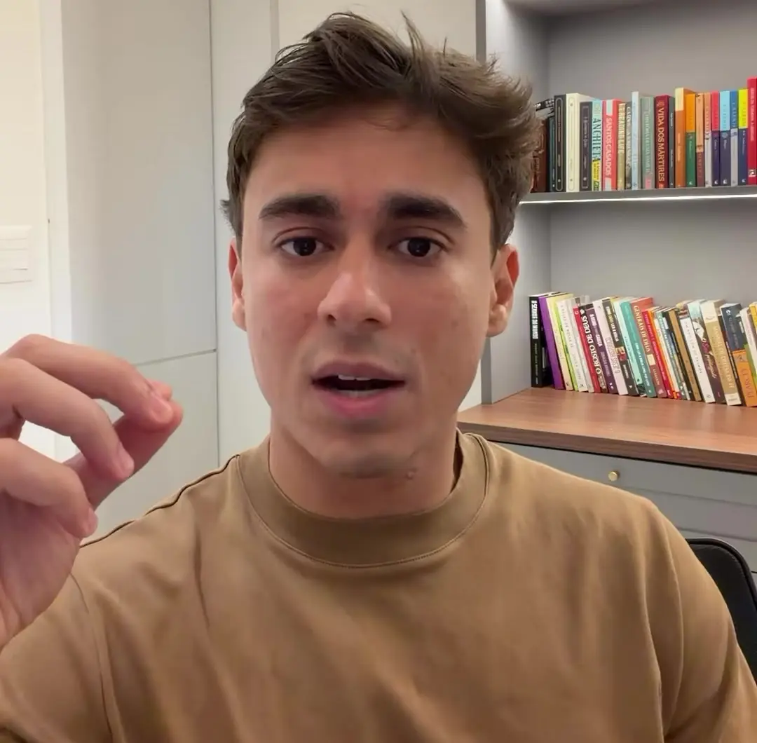 Nikolas Ferreira grava vídeo sobre o boicote e a caridade em frente a uma estante de livros