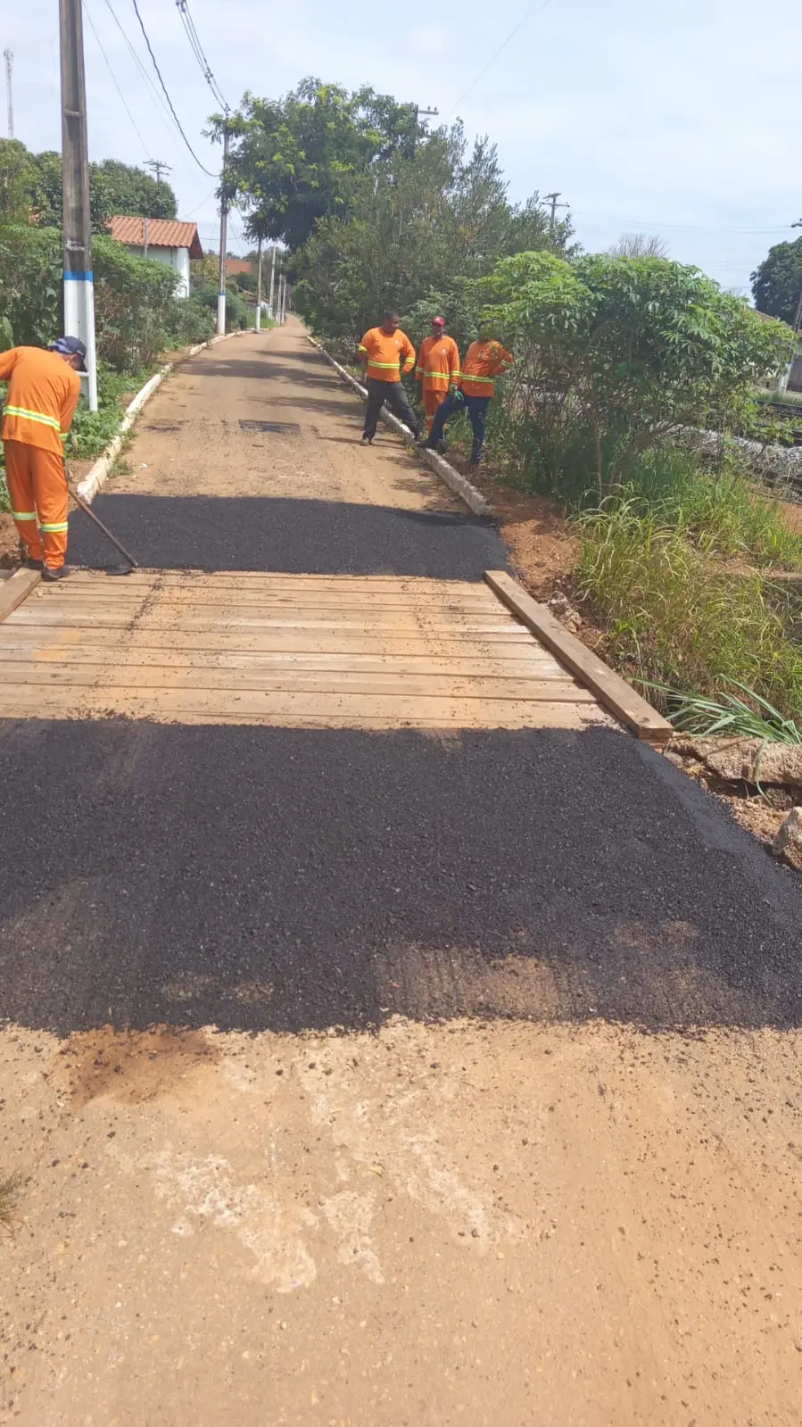 Servidores aplicam asfalto junto a uma ponte de madeira na operação tapa-buracos em Patrocínio