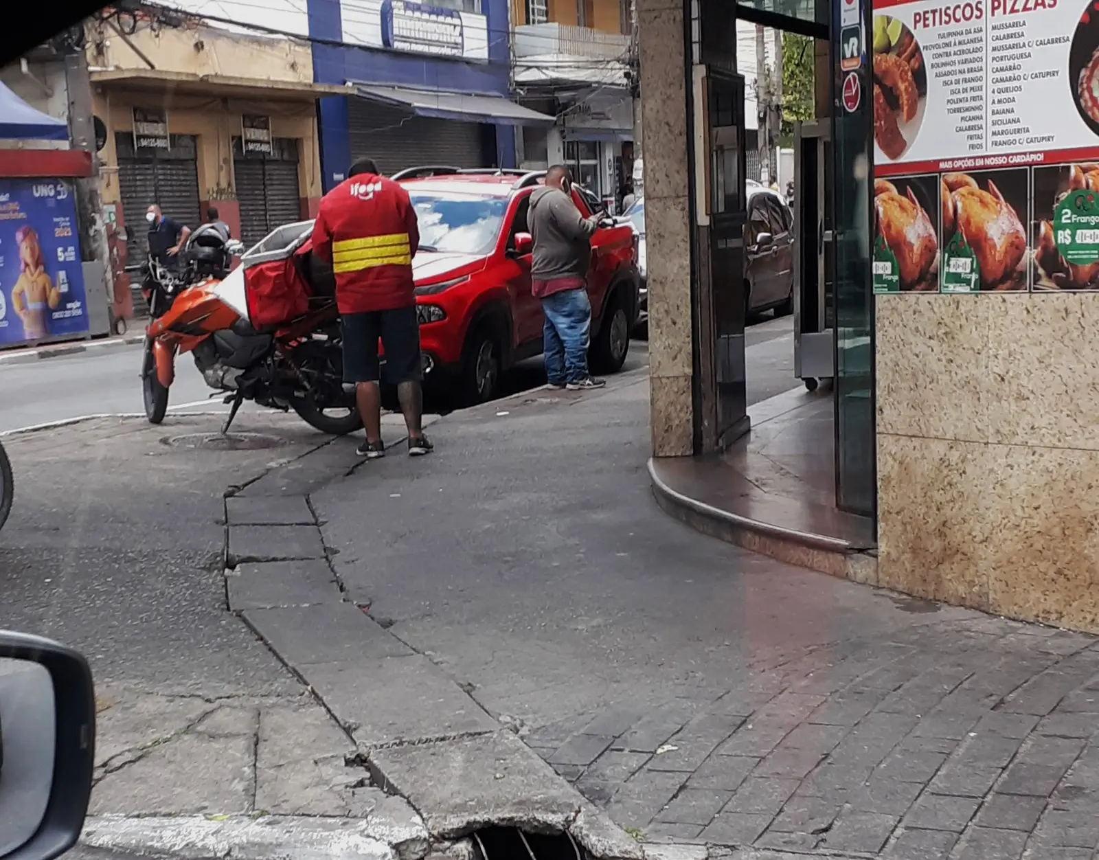 Entregador do iFood estaciona a moto na porta de uma pizzaria, cena comum de quem vai parcelar no iFood