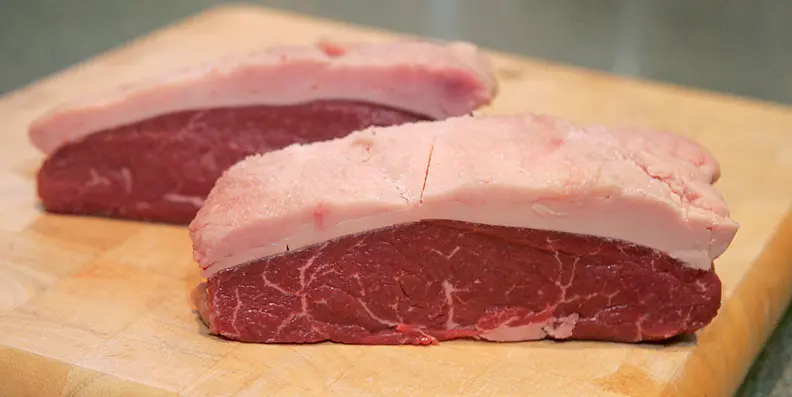 Peças de picanha crua sobre tábua de madeira; o preço da picanha subiu 10,74% em 12 meses